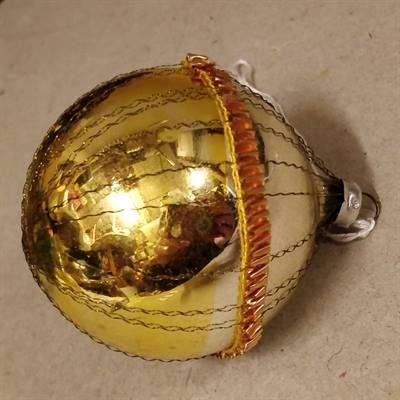 Bånd på midten af gammel julekugle i guld og sølv med tinsel.