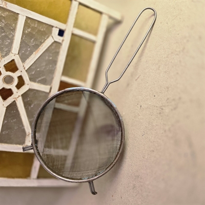 Rund retro metal sigte med håndtag, gammelt køkkengrej.