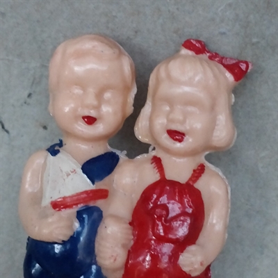 plasik dreng i blåt tøj med skib i favnen hun i rødt tøj med rød sløjfe i håret begge med røde skogammelt legetøj