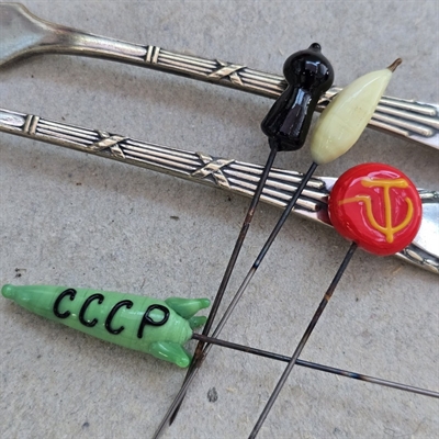 grøn-raket-tekst-cccp-sort-skakbrik-lysegul-frugt-rød-med-gul-hammer-og-sejl-gamle-glas-nipsenåle