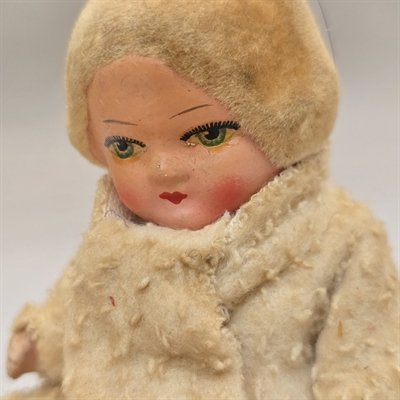 hvid-vinterfrakke-dukke-sidder-paa-kaelk-optraek-gammelt-metal-legetoej-USzone-Germany