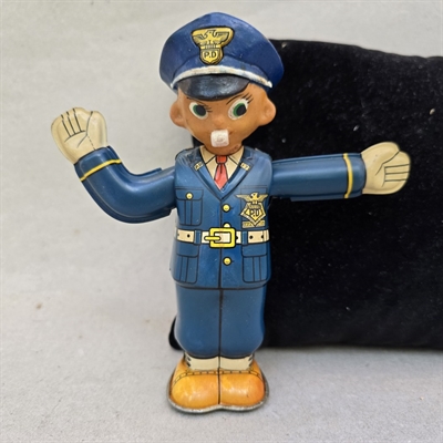 politibetjent-blaa-uniform-kasket-floejte-i -munden-gammelt-mekanisk-metal-legetoej