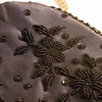 Foto af perlebroderiet på taske. Broderiet forestiller blomster med blade. Broderiet er lidt mørkere brun end stoffet på tasken.
